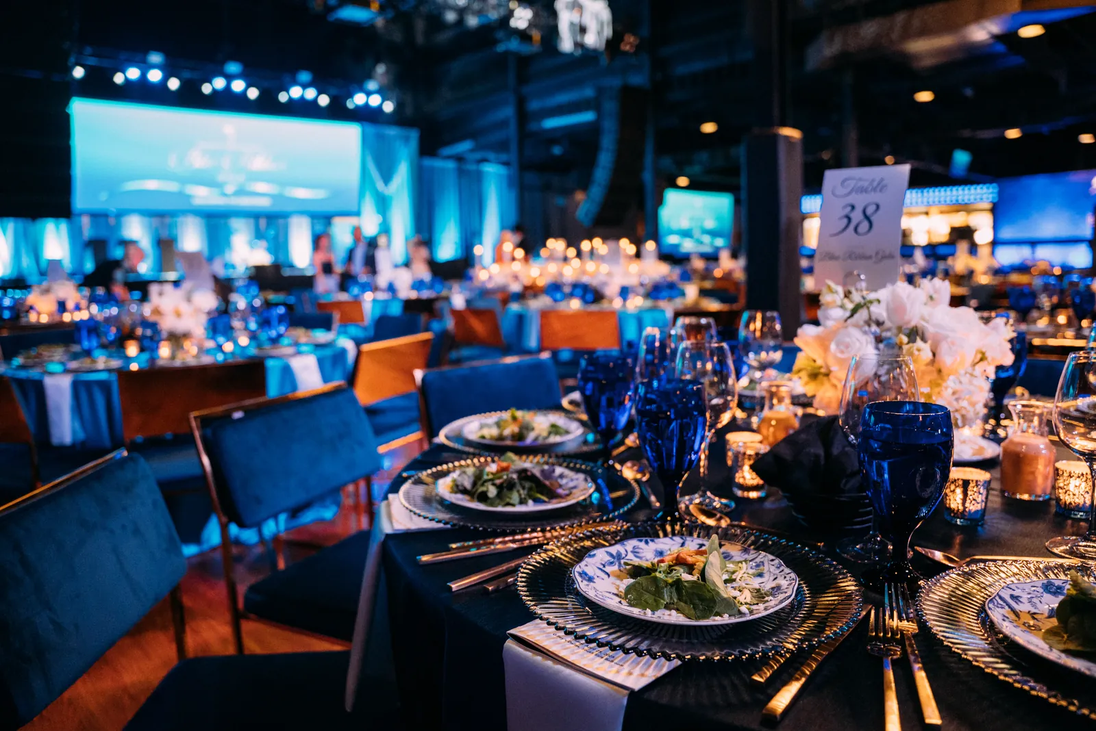 A gala dinner set in a blue-lit ballroom