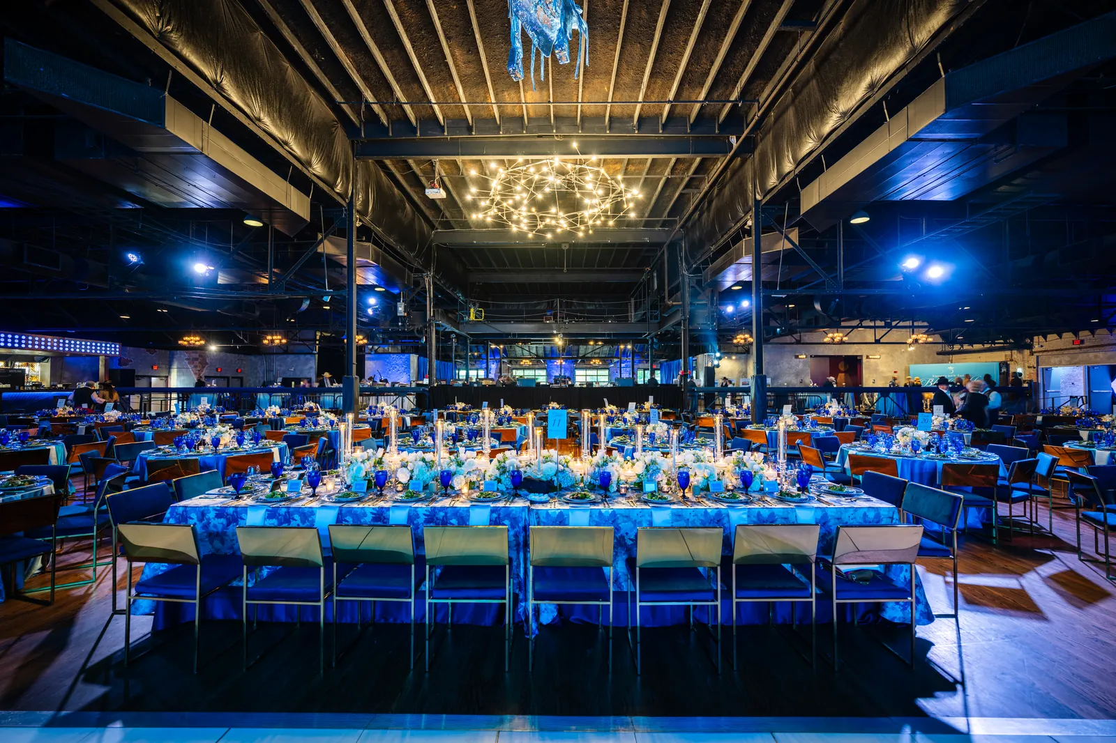 Long banquet tables in a blue-lit venue