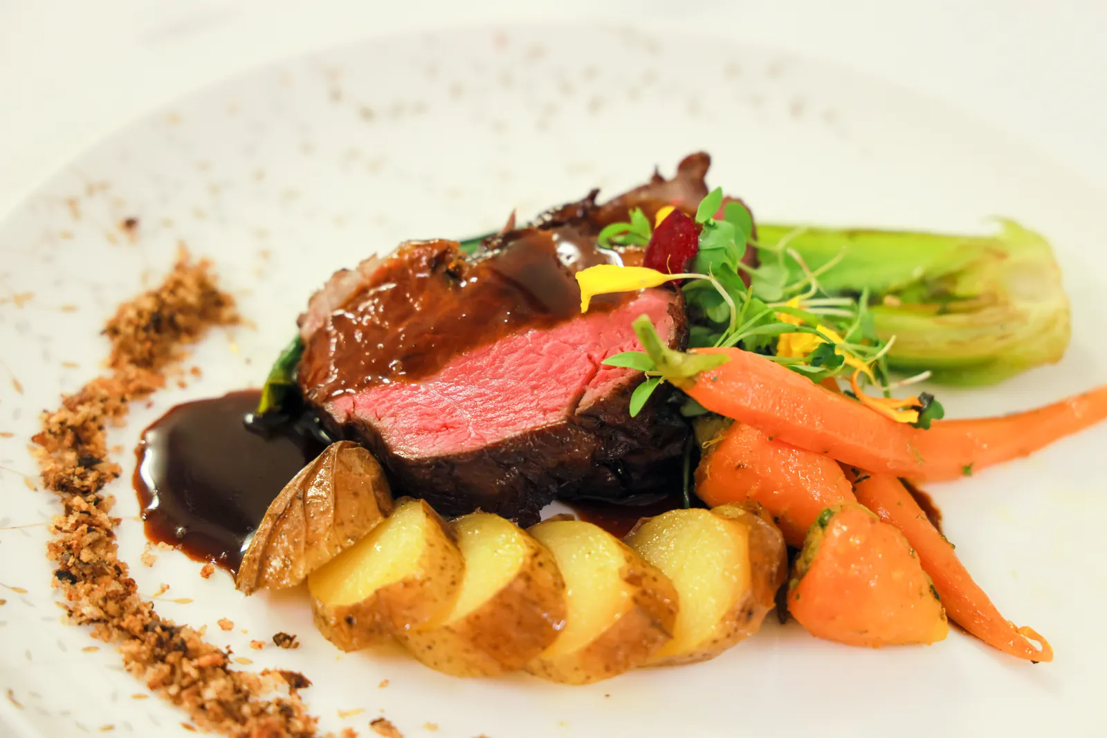 A plated beef course with seasonal vegetables